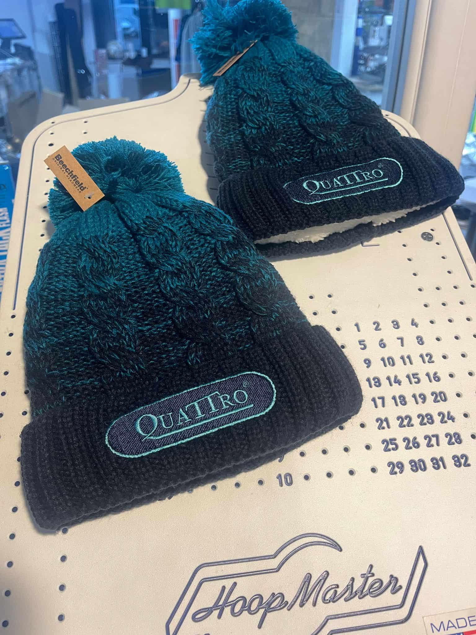 Embroidered Quattro branded beanies on the HoopMaster at the VinylFX workshop — branded workwear and embroidery Cumbria